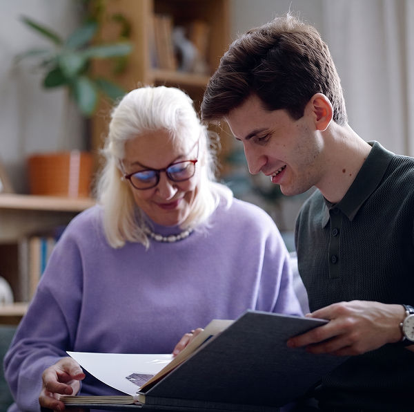a grandson looking at a photo album with his grandmother